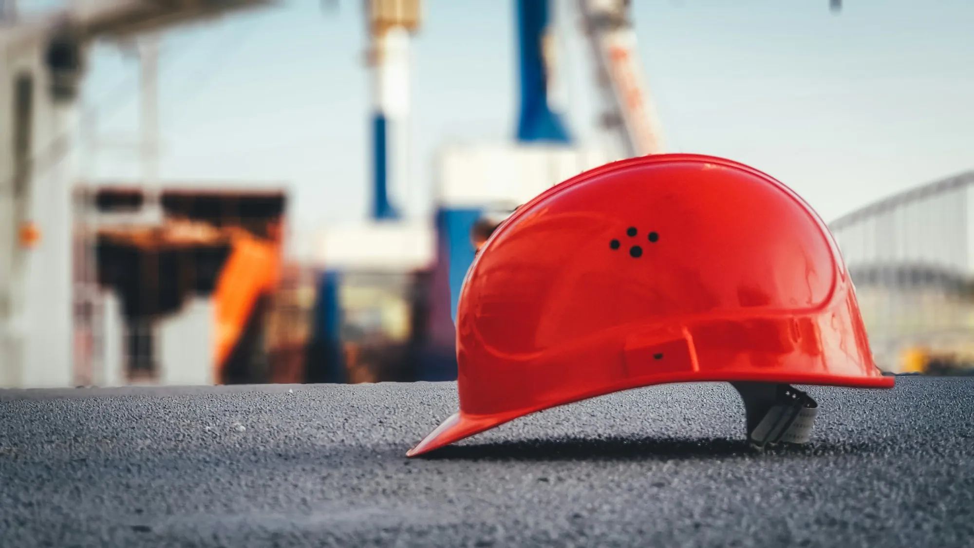 Red hard hat resting on pavement