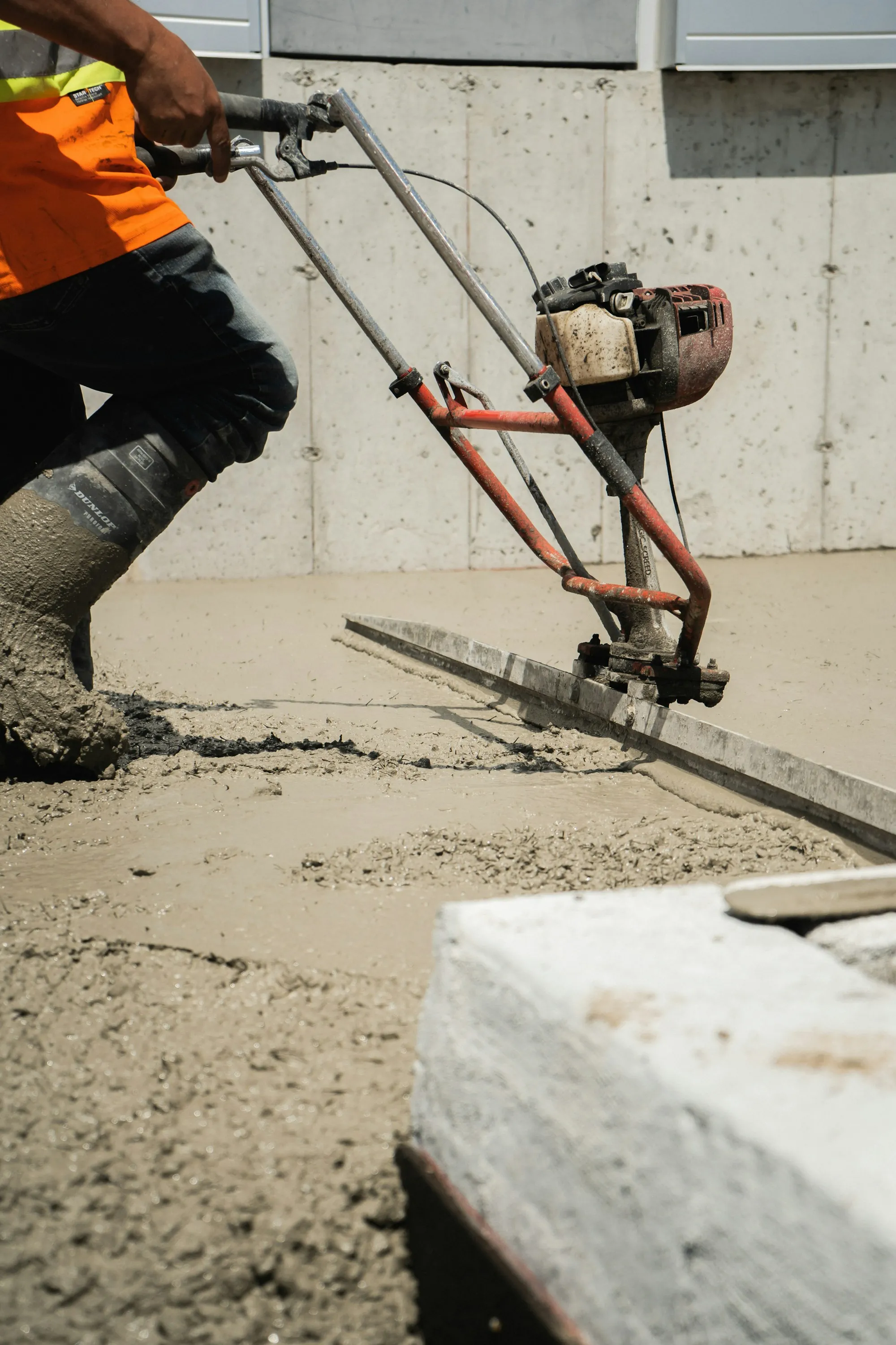Screed leveling a freshly poured concrete slab